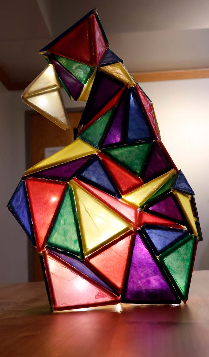 A lamp glows with different colored triangles form to make a geometric shape